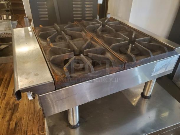 Imperial 4 Burner Range, stainless steel, signs of wear, durable cast iron grates, suitable for commercial kitchens.