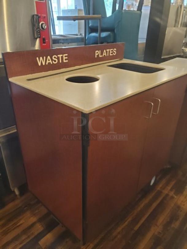 Brown waste station with signage for "Waste" and "Plates." Features dual compartments and cabinet doors.