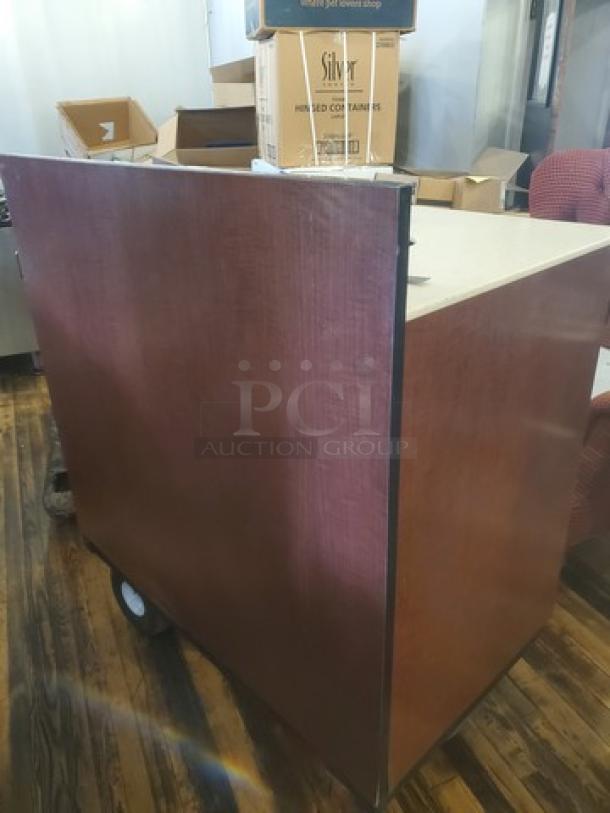 Commercial waste station with wood paneling, cream countertop, and wheels for mobility. Good condition, ideal for kitchen use.