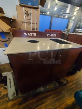 Wooden waste station with labeled waste and plate disposal holes, double doors, and a sturdy countertop. Good condition.