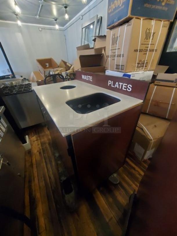 Commercial waste station with dual compartments labeled "WASTE" and "PLATES." Stainless steel top, used condition.