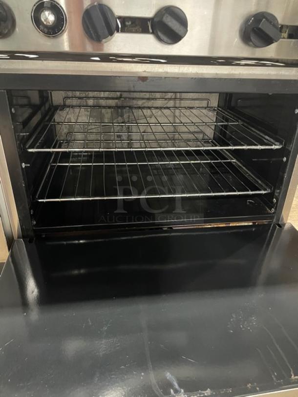 American Range stainless steel gas 6-burner range/oven combo with backsplash, overhead salamander shelf, and wired racks.
