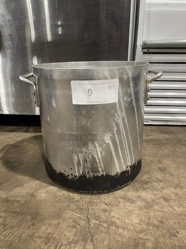 Commercial heavy-duty stock pot with handles, visible wear and darkened base, label indicates auction item number 9.