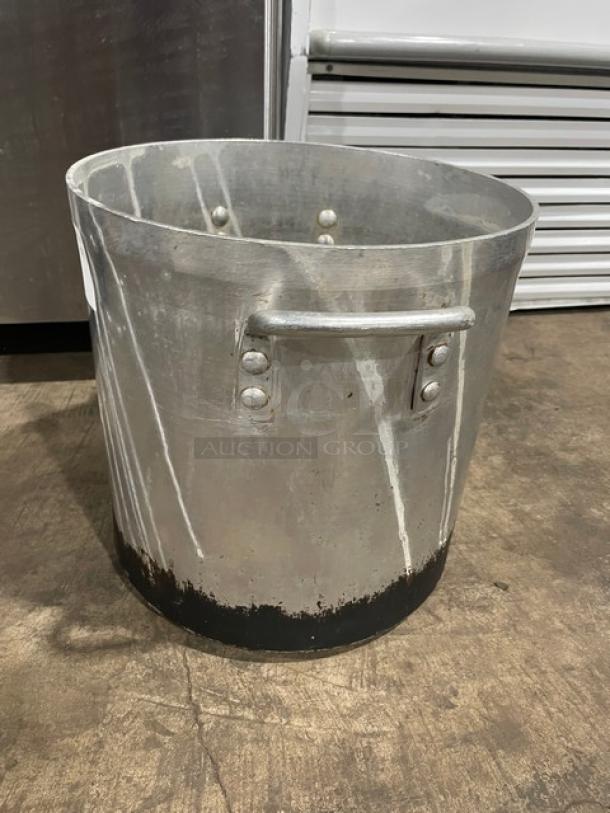 Heavy-duty commercial stock pot with sturdy handles, visible wear on base, ideal for large-scale cooking.