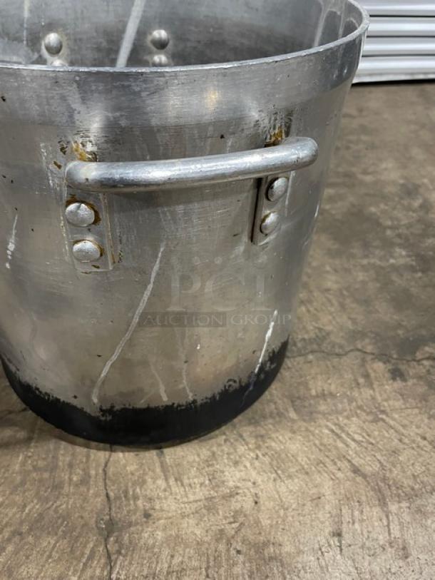 Commercial heavy-duty stock pot with handles; well-used condition, visible wear and blackened base.