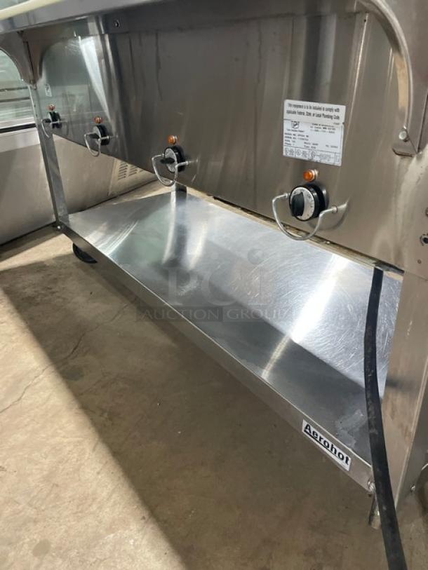 Duke Aero Hot Series 4 Well Steam Table, stainless steel, with sneeze guard, cutting board, single undershelf, on casters.