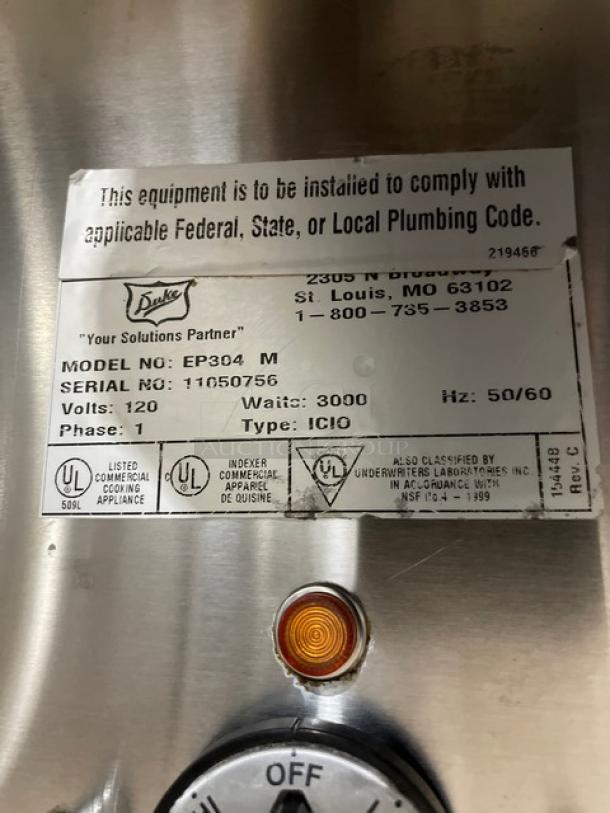 Duke EP304 stainless steel 4-well hot food/steam table. Features sneeze guard, cutting board, single undershelf. Serial: 11050756. 120V, 1 Phase. On casters.