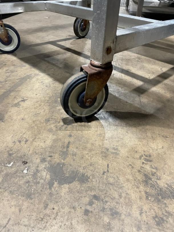 Alexander Industries commercial bun/sheet pan rack, heavy-duty steel, on casters, ideal for transport, some wear visible.