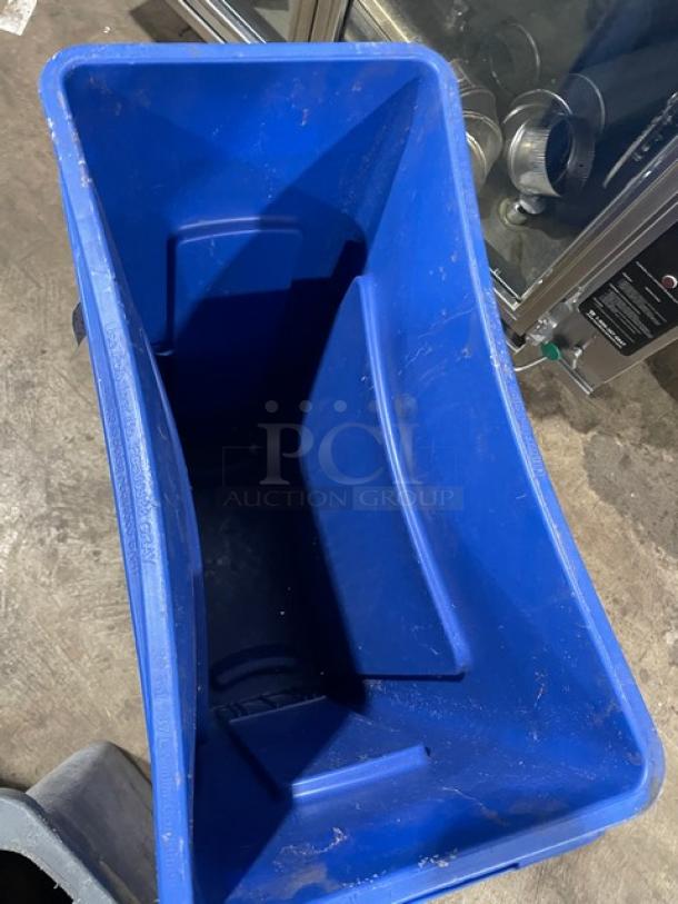 Assorted commercial blue recycle bins and gray trash can, used condition, visible wear, suitable for waste management needs.