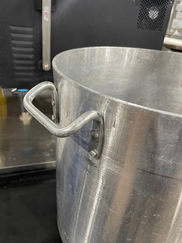 Commercial heavy-duty stock pot with handles, visible wear, metal finish, ideal for large-scale cooking.
