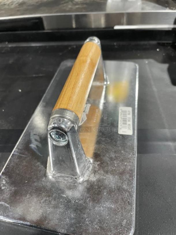 Brand new Vollrath cast aluminum steak weight, model 47709, with waffle-patterned grid and wooden grip handle.