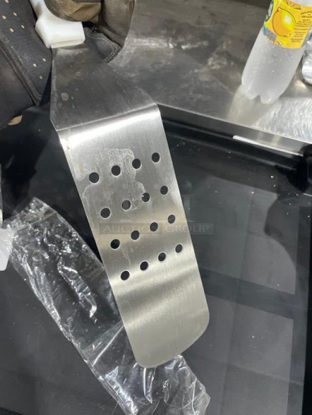 ABC Commercial Stainless Steel Perforated Turner, Model PFT10P, with white grip handle, minor surface marks.