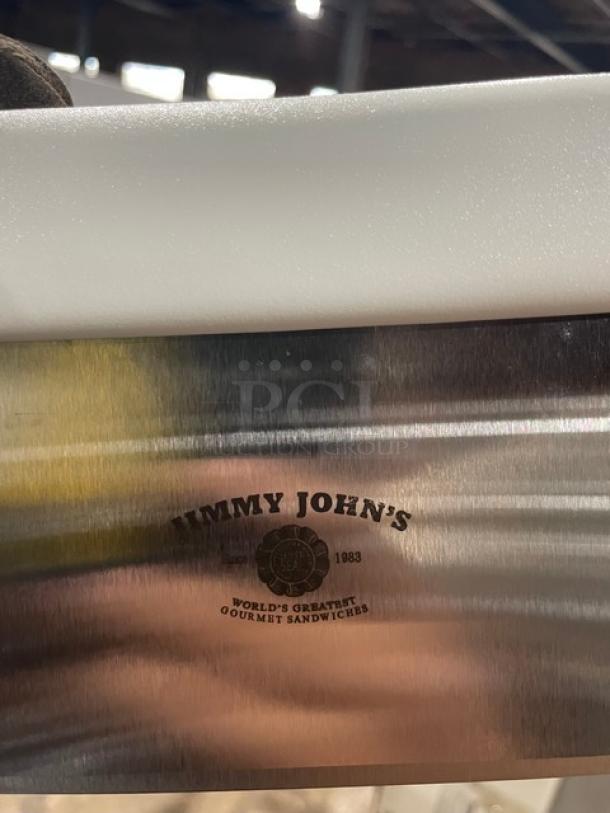 Brand new Jimmy John's stainless steel dough cutter with white grip handle. Features Jimmy John's logo.