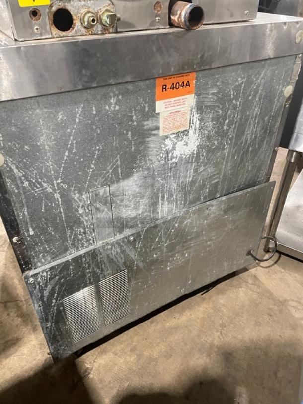 Delfield under-counter refrigerator, stainless steel, solid single door, polly-coated wire rack, on casters. Visible R-404A label.