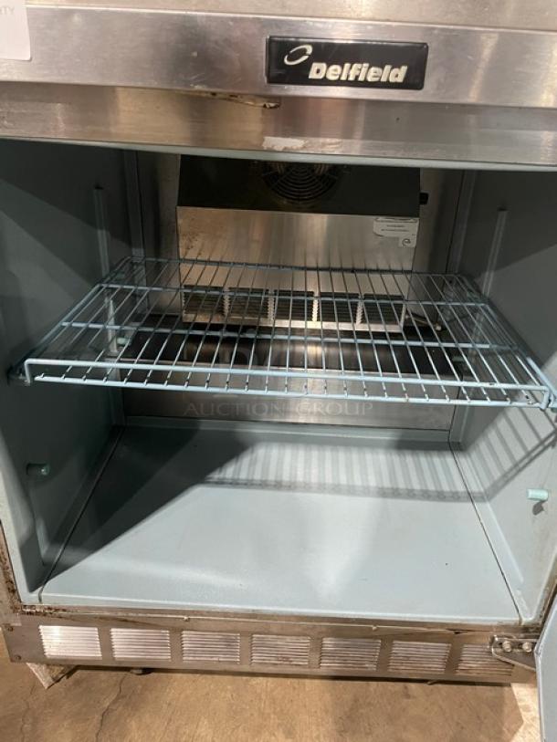 Delfield stainless steel single door under counter refrigerator, poly-coated wire rack, on casters, good condition.