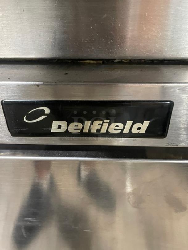 Delfield stainless steel under counter refrigerator, single door, with poly-coated wire rack, on casters. Brand label visible.