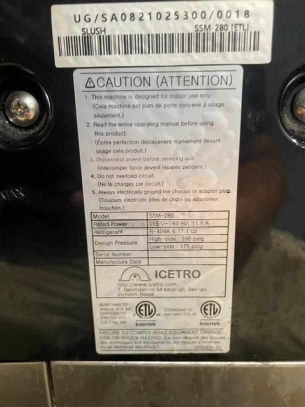 Icetro SSM-280 twin slushy machine with clear hoppers and drip tray, 115V. Features caution label and specifications.