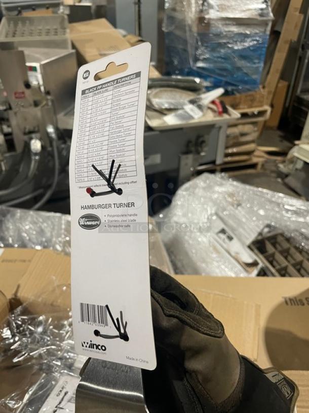 Brand new Winco Winware TKP-61 stainless steel offset hamburger turner with a black grip handle, tags visible.