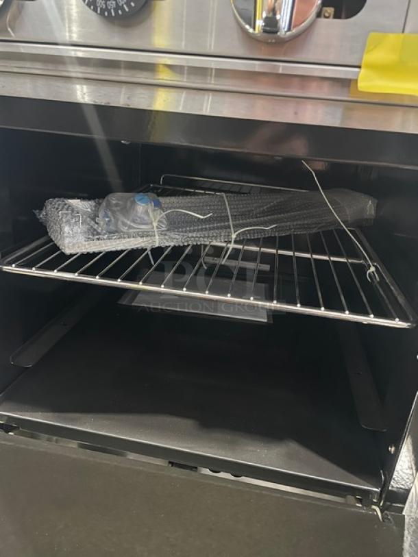 Brand new Atosa Cook Rite ATO-24G natural gas griddle range with stainless steel overshelf and rack, on casters.