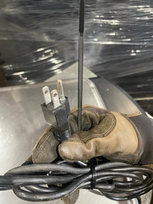 Hobart HTi commercial scale plug with glove, cable, and zip tie shown in foreground, indicating connectivity and hardware details.