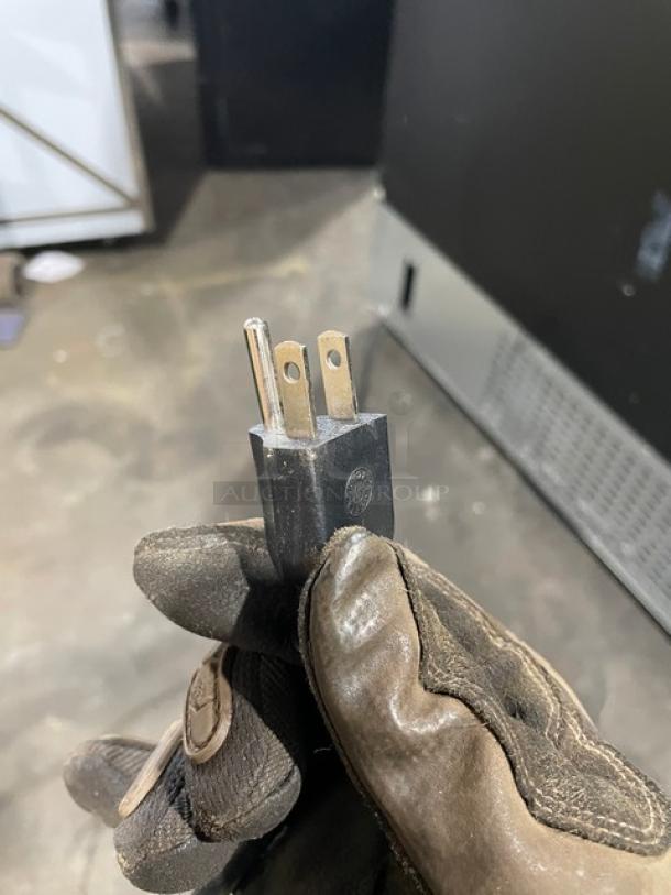 Alt text: An electrical plug held by a gloved hand, associated with a Kool-It Model KGM75 commercial refrigerator.