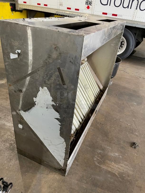 Commercial stainless steel kitchen exhaust hood with filter and electric fan, showing wear. Suitable for restaurant use.