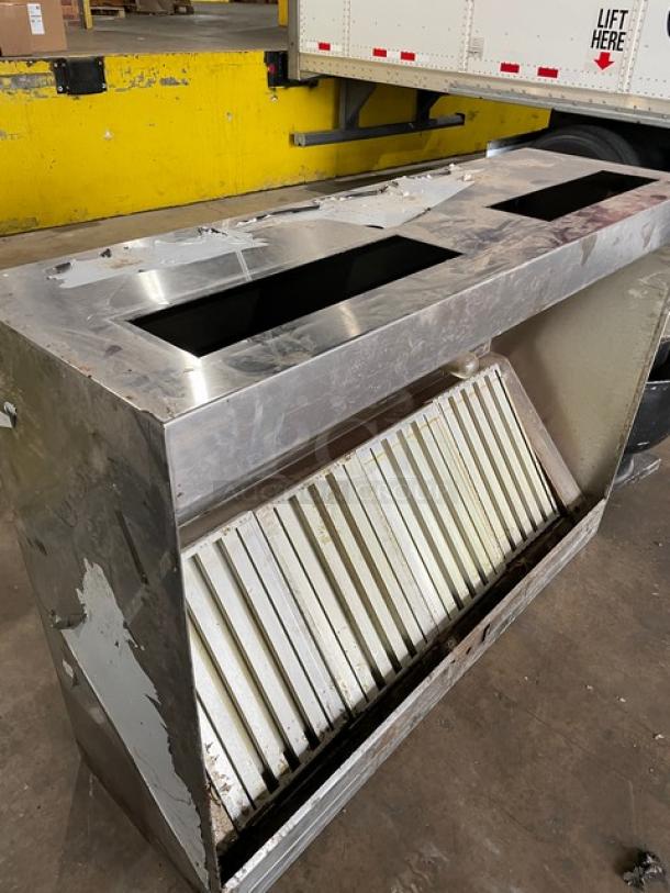 Stainless steel kitchen exhaust hood with filter and electric exhaust fan, showing signs of wear.
