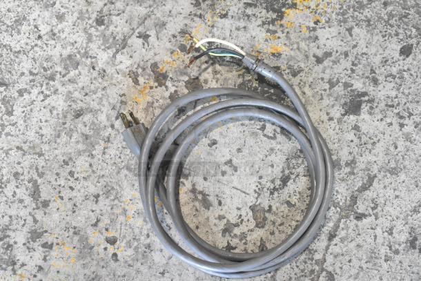 A coiled gray power cable on a concrete surface, showing a standard plug on one end and exposed wires on the other.