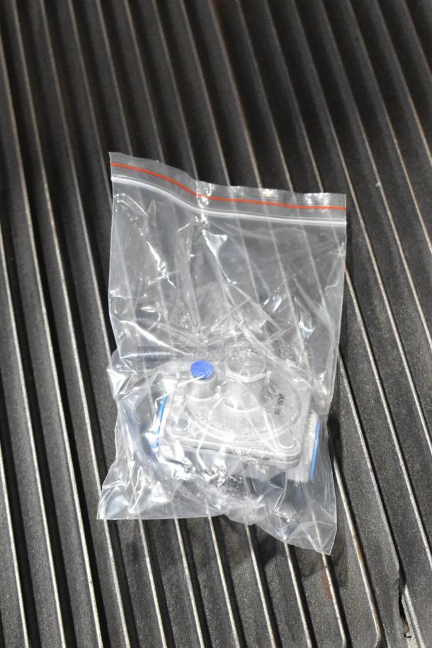 Stainless steel gas charbroiler top view with packaged parts on grates, Cooking Performance Group 351CRCPG24NL, 80,000 BTU.