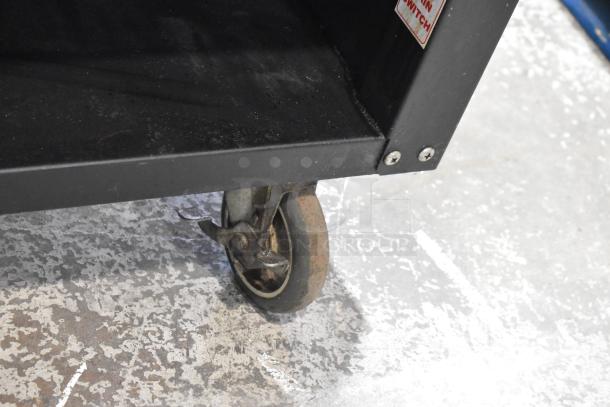 Lakeside metal bakery display case on commercial casters, 125 Volts, 1 Phase. Shows wheel and lower section details.
