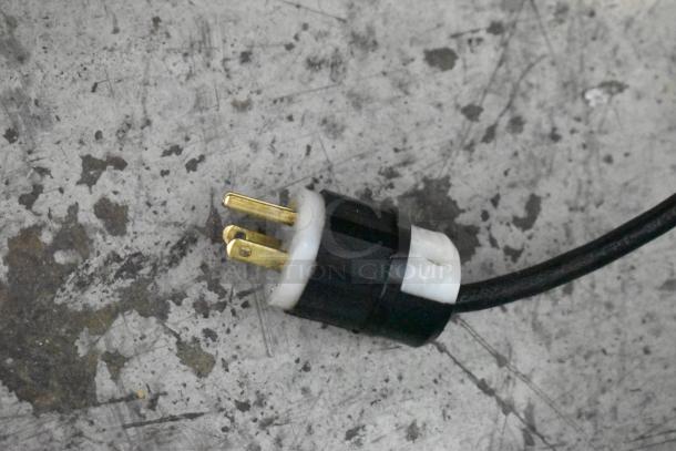 Lakeside bakery display case plug, 125 volts, shown on a worn surface; features a three-prong connection.