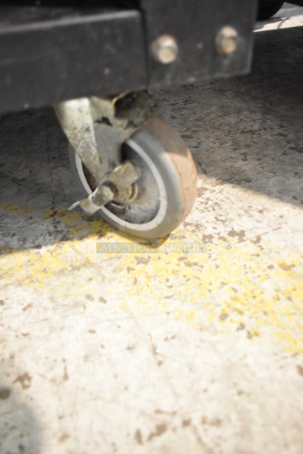 Close-up view of a caster wheel on a Vulcan 1015021 bakery display case. Sturdy metal construction, in used condition.