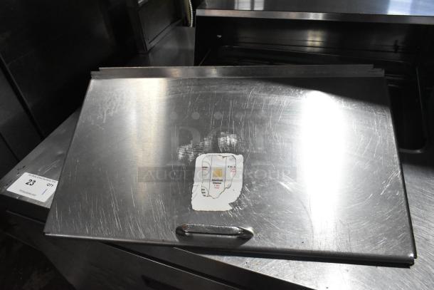 Stainless steel Delfield UCD4464N-12-DD5 prep table lid. Visible wear and a worn label detail on surface.
