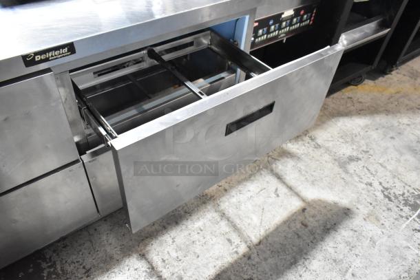 Delfield UCD4464N-12-DD5 stainless steel prep table with four open drawers, shown on commercial casters.