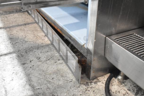 Delfield UCD4464N-12-DD5 stainless steel prep table, showing commercial casters and part of an undershelf. Visible wear.