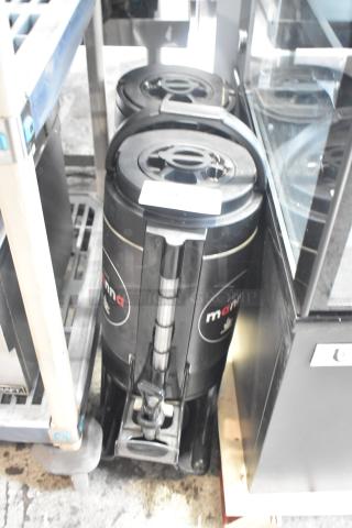 Two black Manna satellite servers, side by side, with dispensing spigots. In good condition, suitable for beverages.