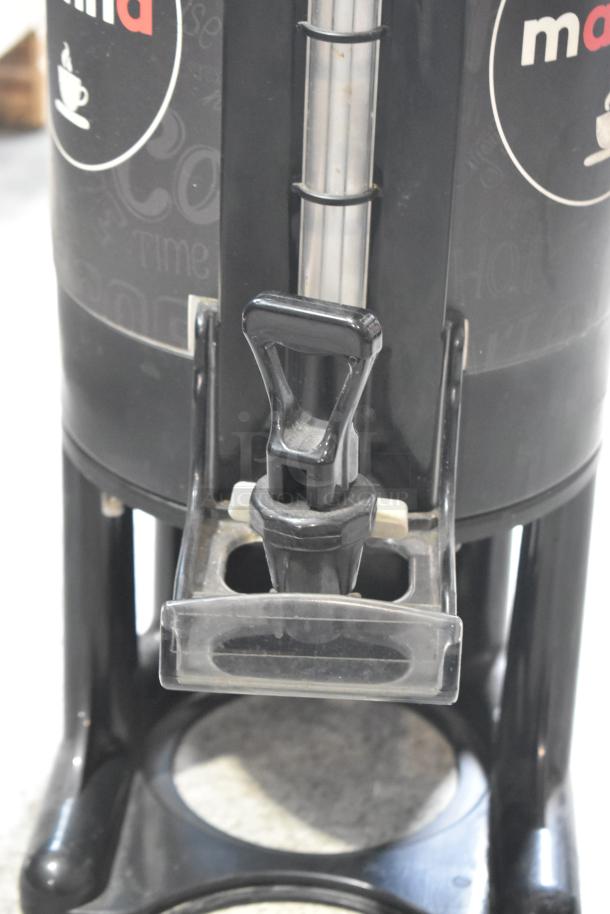 Black satellite server with dispenser tap and "m" logo. Standing on a sturdy base, ideal for hot beverages.