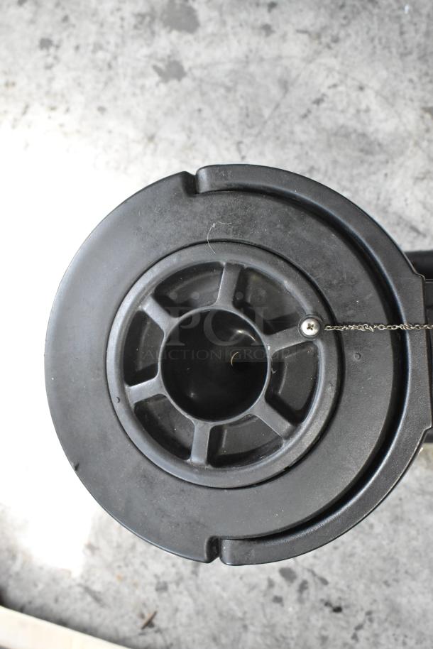Close-up of a black satellite server component, featuring a circular design with a chain attachment, on a concrete surface.