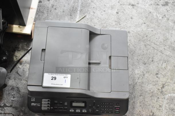 Brother MFC-L2700DW countertop scanner copier printer, gray, with visible auction tag. Appears in used condition.