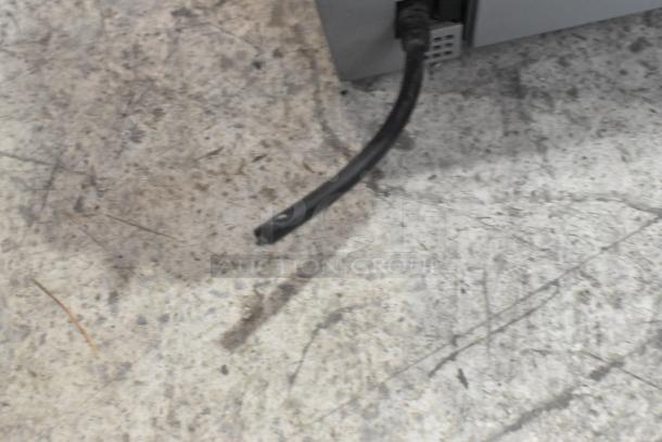 Brother MFC-L2700DW printer cable detail on concrete surface.