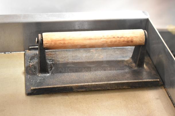 Cookline Stainless Steel Griddle, durable gas-powered flat top, commercial use. Wooden handle shows wear. Ideal for robust cooking.