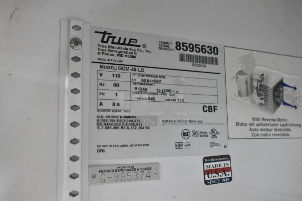 True GDM-45-LD cooler label details voltage, refrigerant type, and model info. Made in USA, has PepsiCo property tag.