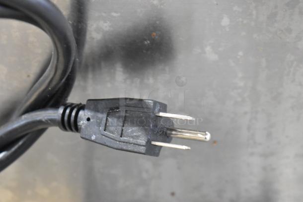 Southwood RG7 rotisserie oven plug. Two-pronged, black cord, connected to stainless steel appliance.