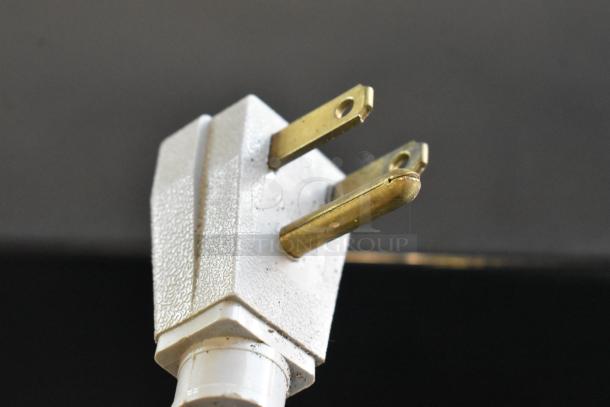 Close-up of a power plug for a 2019 True GDM-41SL-48-HC-LD commercial cooler, showing prongs and textured surface.