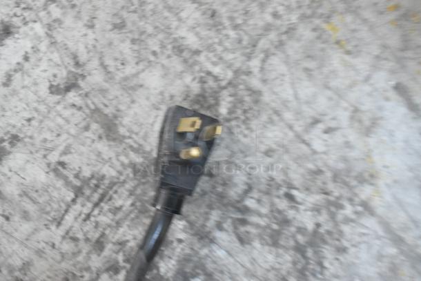 Electrical plug for the True GDM-12 commercial cooler, shown on a textured surface. Plug is compatible with 115 volts, 1 phase.