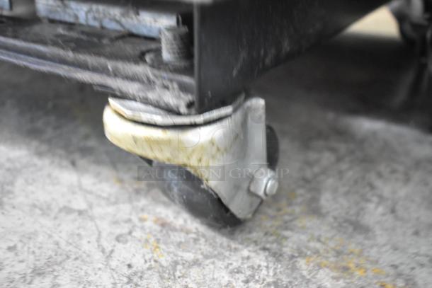 Close-up of a caster wheel from a 2019 True T-19F-HC commercial freezer. Shows wear and dirt accumulation.