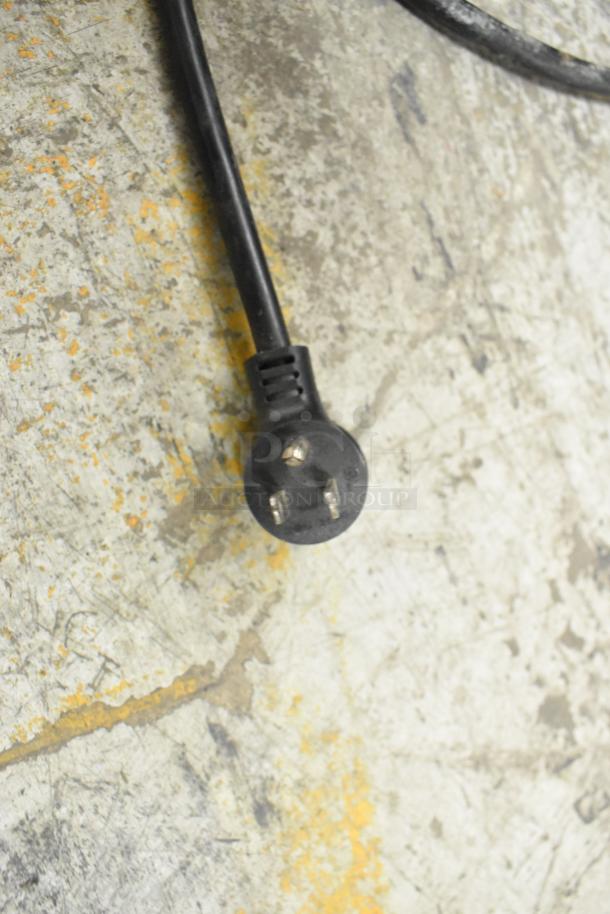 Power plug for 2019 True T-19F-HC commercial freezer. Black cord, three-prong plug on concrete floor.