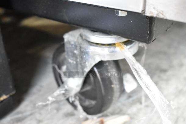 Close-up of a caster with protective wrap on a 2022 True T-35-HC stainless steel commercial cooler.