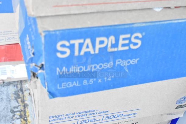 Five boxes of Staples multipurpose legal paper, 8.5"x14", plus 8 extra reams. Appears in original packaging. Slight box wear.