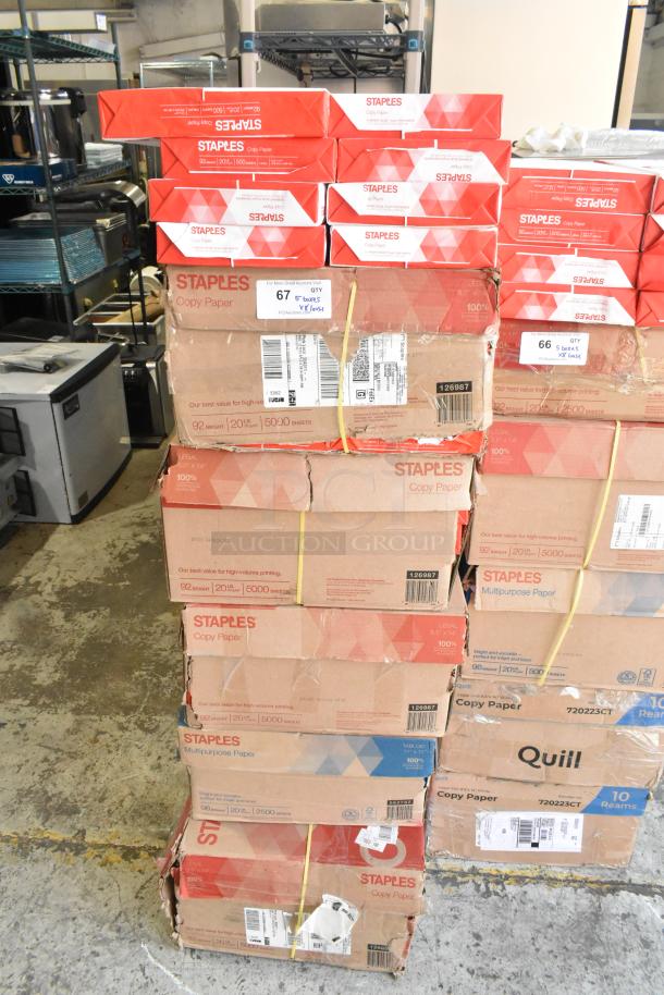 Stack of Staples copy paper boxes with an extra 8 reams, totaling over 25,000 sheets. Some boxes show wear. Perfect for bulk printing needs.